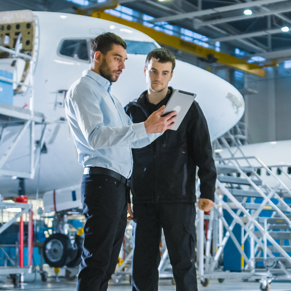 Ingenieure vor Flugzeugen, in Hangar